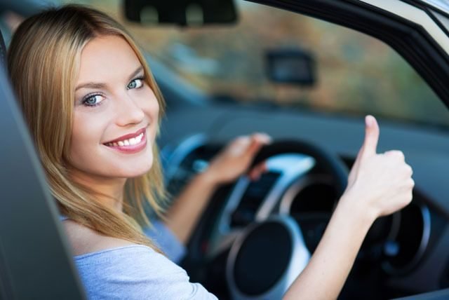 Une conductrice souriante au volant, pouce levé